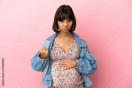 Young pregnant woman over isolated pink background with unhappy expression © luismolinero