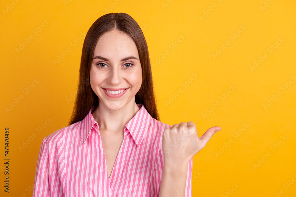 Photo of young cheerful lady indicate thumb empty space advertisement discount isolated over yellow color background Photo of young cheerful lady indicate thumb empty space advertisement discount isolated over yellow color background