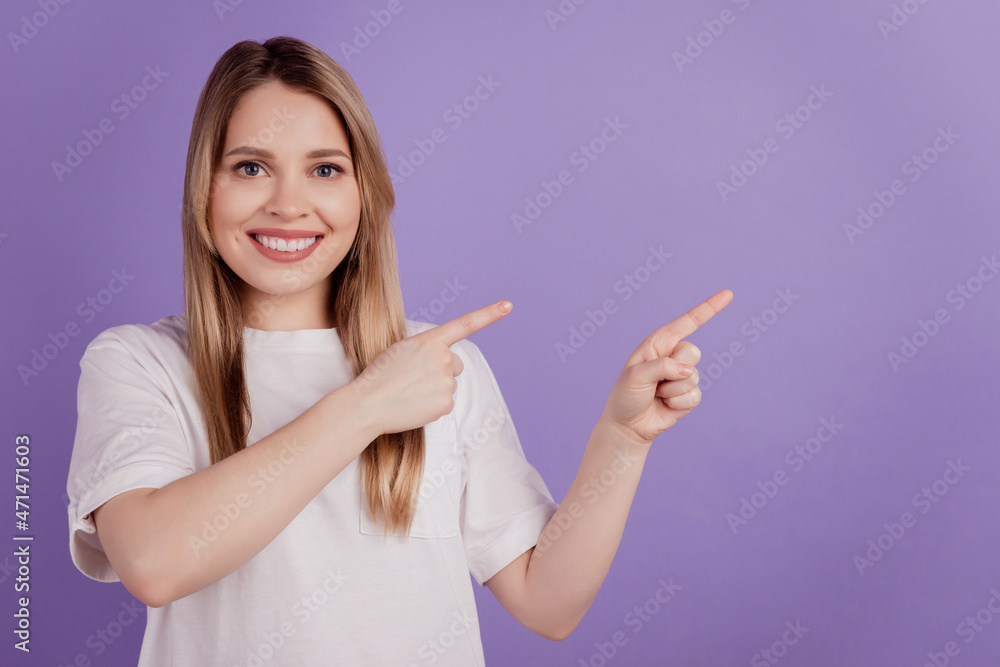 Photo of cheerful promoter lady direct fingers empty space wear casual clothes on purple background Photo of cheerful promoter lady direct fingers empty space wear casual clothes on purple background