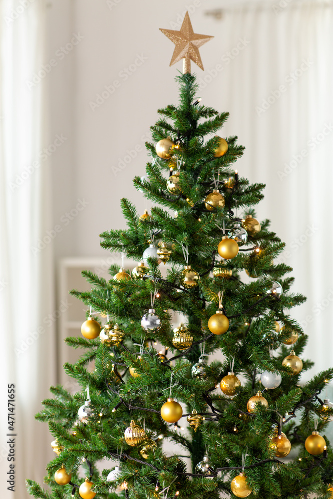 winter holidays, new year and celebration concept - green artificial christmas tree decorated with toys at home