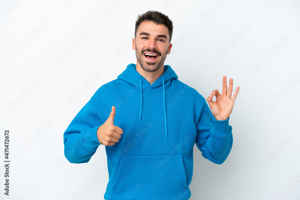 Young caucasian man isolated on white background showing ok sign and thumb up gesture Young caucasian man isolated on white background showing ok sign and thumb up gesture