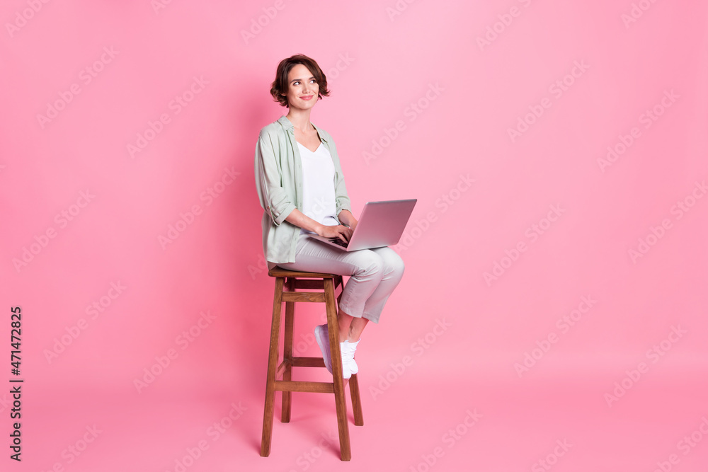 Full size photo of business bob hairdo young lady sit laptop look empty space wear grey green look isolated on pink background Full size photo of business bob hairdo young lady sit laptop look empty space wear grey green look isolated on pink background