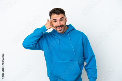 Young caucasian man isolated on white background making phone gesture. Call me back sign © luismolinero