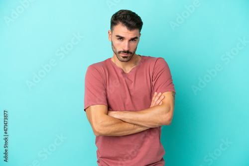 Young caucasian man isolated on blue background with unhappy expression