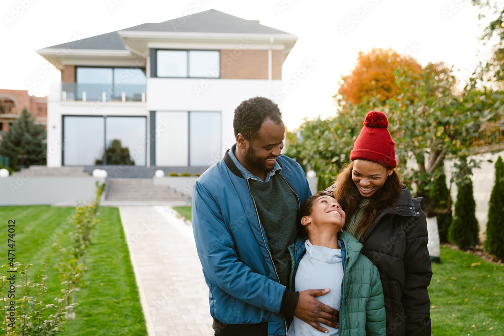 Black family smiling and talking together while standing by house