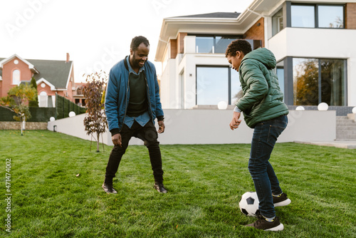 Black man and his son playing football on courtyard