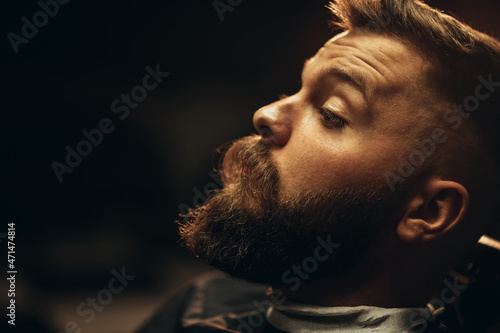 Close shot of a young man beard while he is sitting at a barbershop