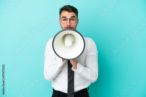 Business caucasian man isolated on blue background shouting through a megaphone