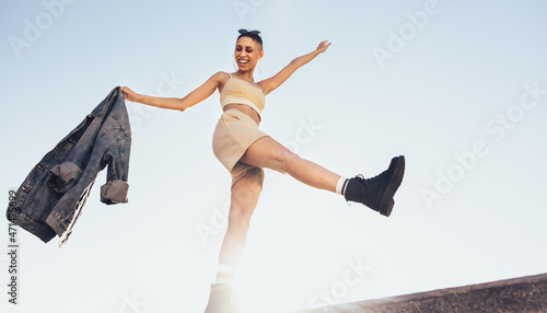 Vibrant young woman kicking the air outdoors