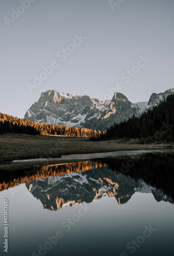 A mountain lake in the Dolomites. The mountains and the rest of the landscape are reflected in the lake. It is autumn. The Calaita lake