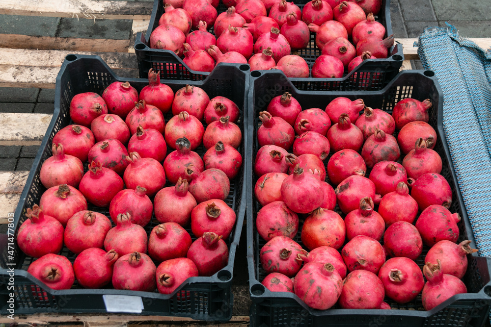 Ripe pomegranate fruits in open plastic boxes. Selling exotic fruits in the market. The fruits of the pomegranate are eaten raw, in cooked dishes, in drinks, to obtain pomegranate juice. Ripe pomegranate fruits in open plastic boxes. Selling exotic fruits in the market. The fruits of the pomegranate are eaten raw, in cooked dishes, in drinks, to obtain pomegranate juice.
