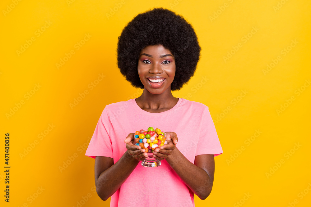 Photo of young black girl happy positive smile hold jar candy sweets yummy isolated over yellow color background Photo of young black girl happy positive smile hold jar candy sweets yummy isolated over yellow color background