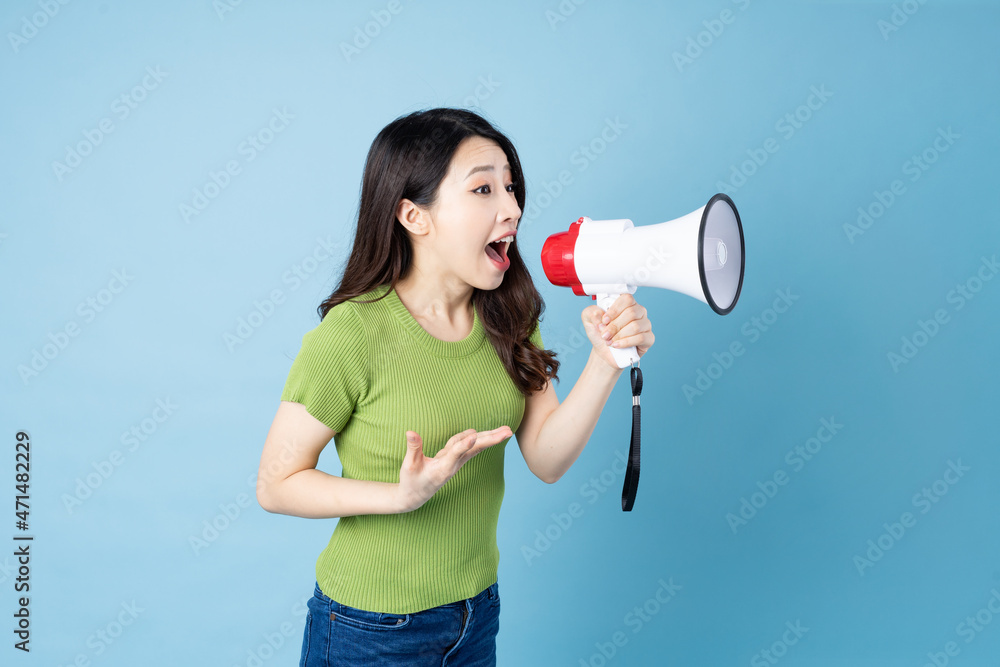 Asian girl portrait holding speaker, isolated on blue background Asian girl portrait holding speaker, isolated on blue background