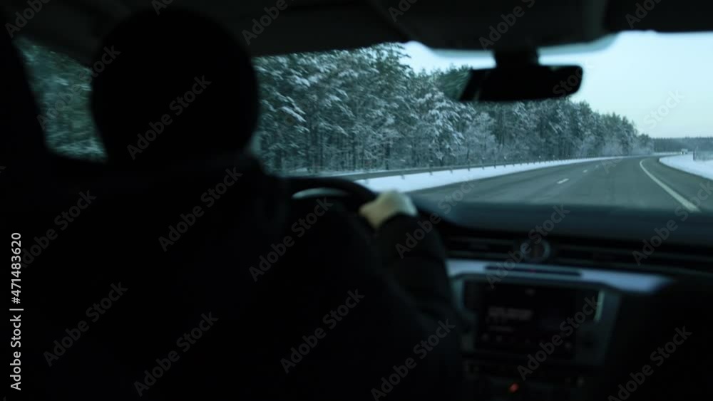 A male driver drives a car on an evening winter road in cold weather. Winter car driving concept, long distance trip, close-up A male driver drives a car on an evening winter road in cold weather. Winter car driving concept, long distance trip, close-up