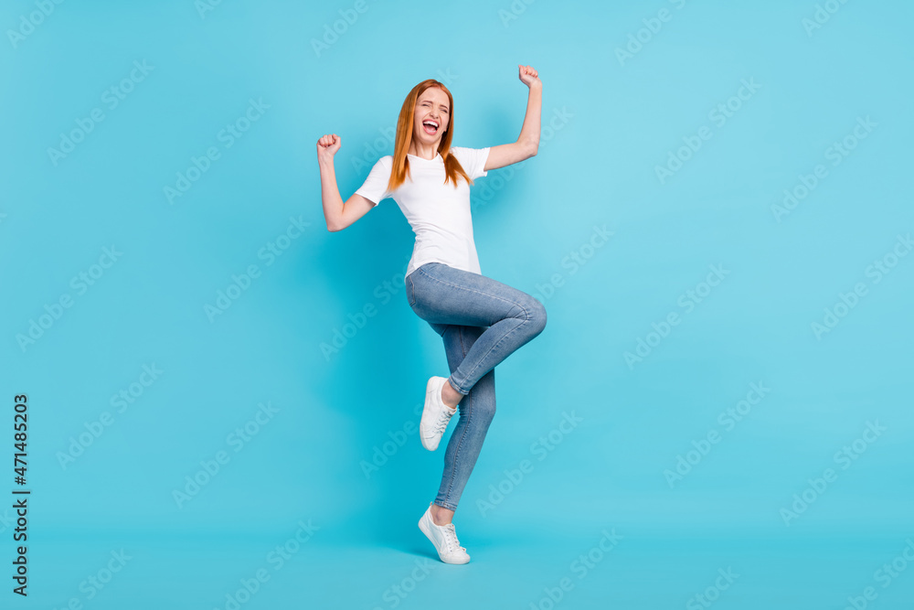 Full size photo of young girl happy positive smile celebrate victory success fists hands isolated over blue color background Full size photo of young girl happy positive smile celebrate victory success fists hands isolated over blue color background