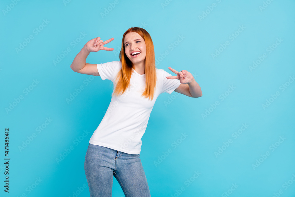 Fototapeta premium Photo of young girl happy positive smile show peace cool v-sign look empty space isolated over blue color background
