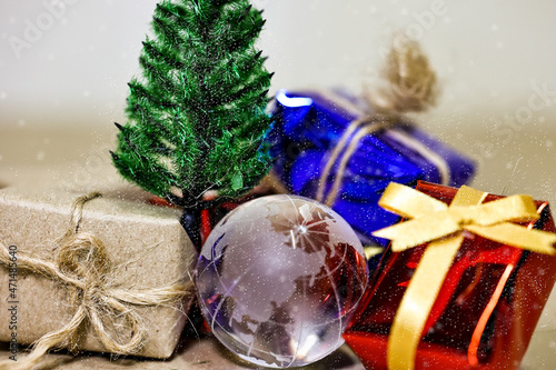 Merry Christmas, Happy New Year and Boxing day concept. Present boxes, world gloge crystal glass, pine tree and house models on light brown background. photo