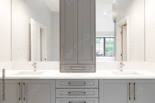 A gray vanity in a large luxurious bathroom with granite counter tops and chrome fixtures. 