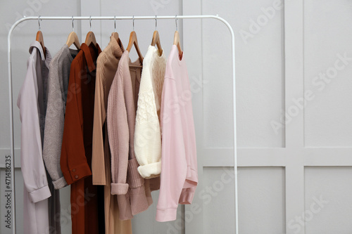 Rack with different stylish clothes near grey wall. Space for text © New Africa