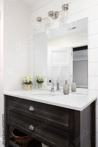 A beautiful bathroom with a shiplap wall  dark wood vanity cabinet  and a marble countertop. 