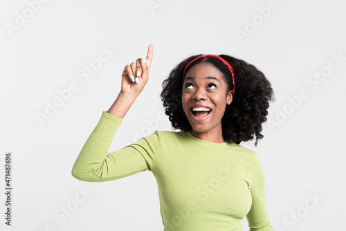 Young black woman smiling and pointing finger upward