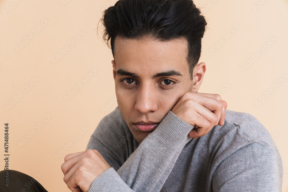 Young middle eastern man looking at camera while sitting on floor Young middle eastern man looking at camera while sitting on floor