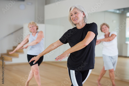 Positive senior women in sportswear dancing in fitness room.