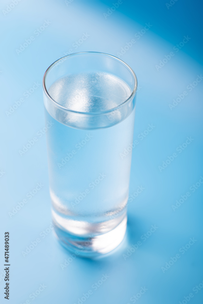 Glass of pure cold water on a blue background. Glass of pure cold water on a blue background.