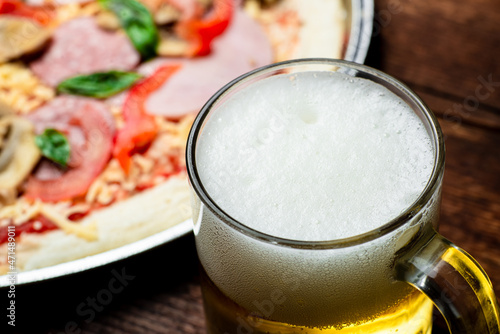 Glass of beer close up on pizza background.