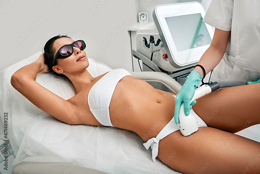 Woman receiving laser epilation on bikini zone at beauty clinic. Bikini  zone laser hair removal for a woman using a medical laser Photos | Adobe  Stock