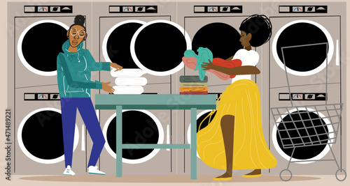 Lesbian couple putting clothes in the dryer at the laundromat 