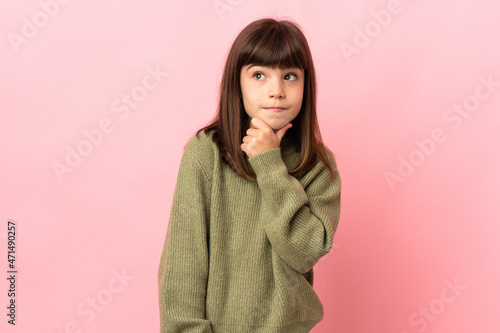 Little girl isolated on pink background having doubts and thinking © luismolinero