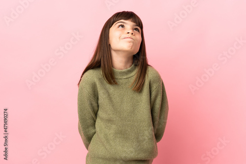 Little girl isolated on pink background and looking up © luismolinero