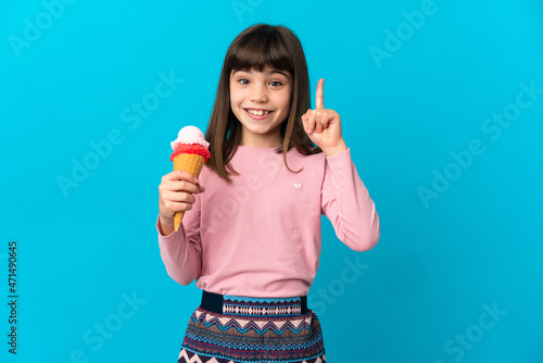 Little girl with a cornet ice cream isolated on blue background pointing up a great idea
