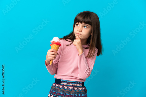 Little girl with a cornet ice cream isolated on blue background and looking up