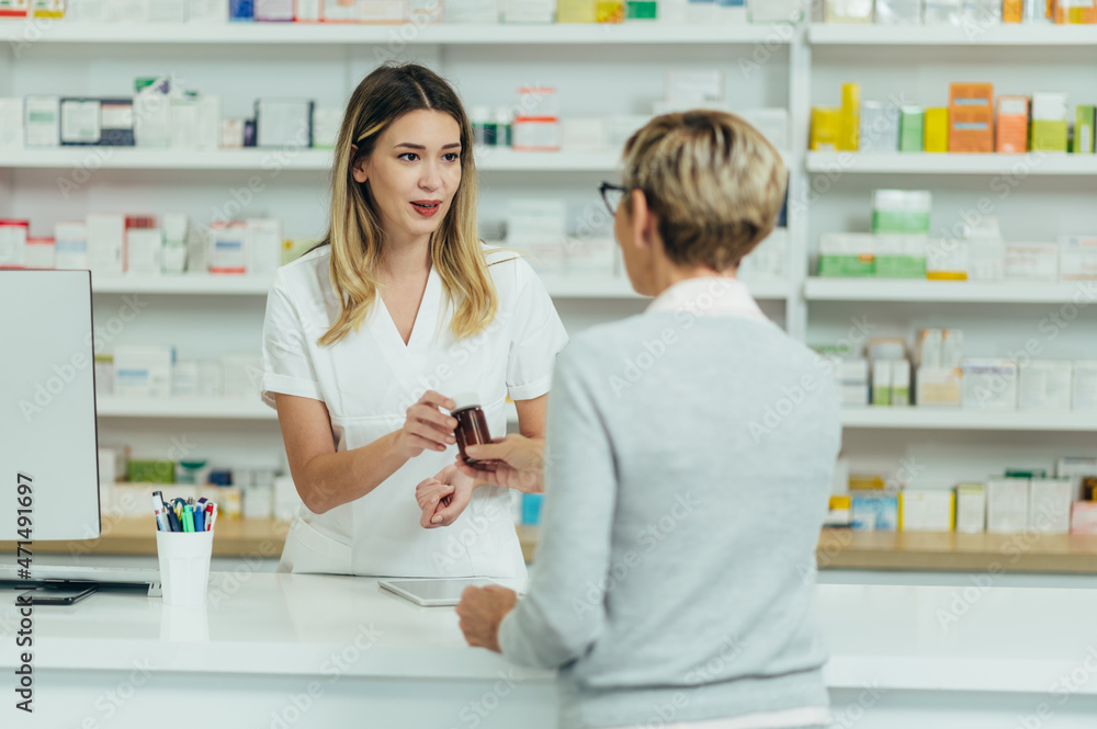Female pharmacist selling medications at drugstore to a senior woman customer Female pharmacist selling medications at drugstore to a senior woman customer