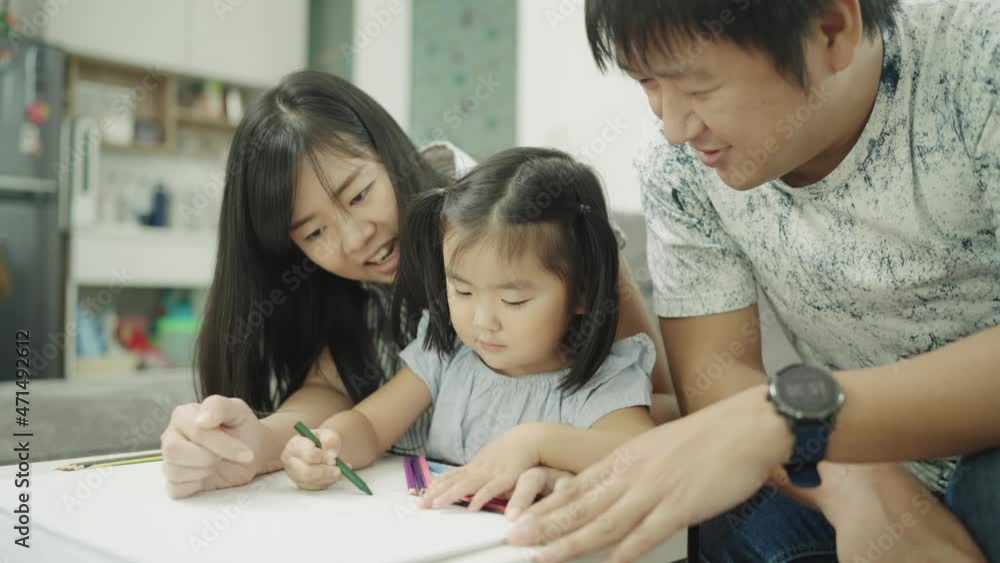 Asian Family parents play with daughters at the home table. adult parent father teaching cute small children girls learning creative activity enjoying happy high five with daddy and mom on holiday. Asian Family parents play with daughters at the home table. adult parent father teaching cute small children girls learning creative activity enjoying happy high five with daddy and mom on holiday.