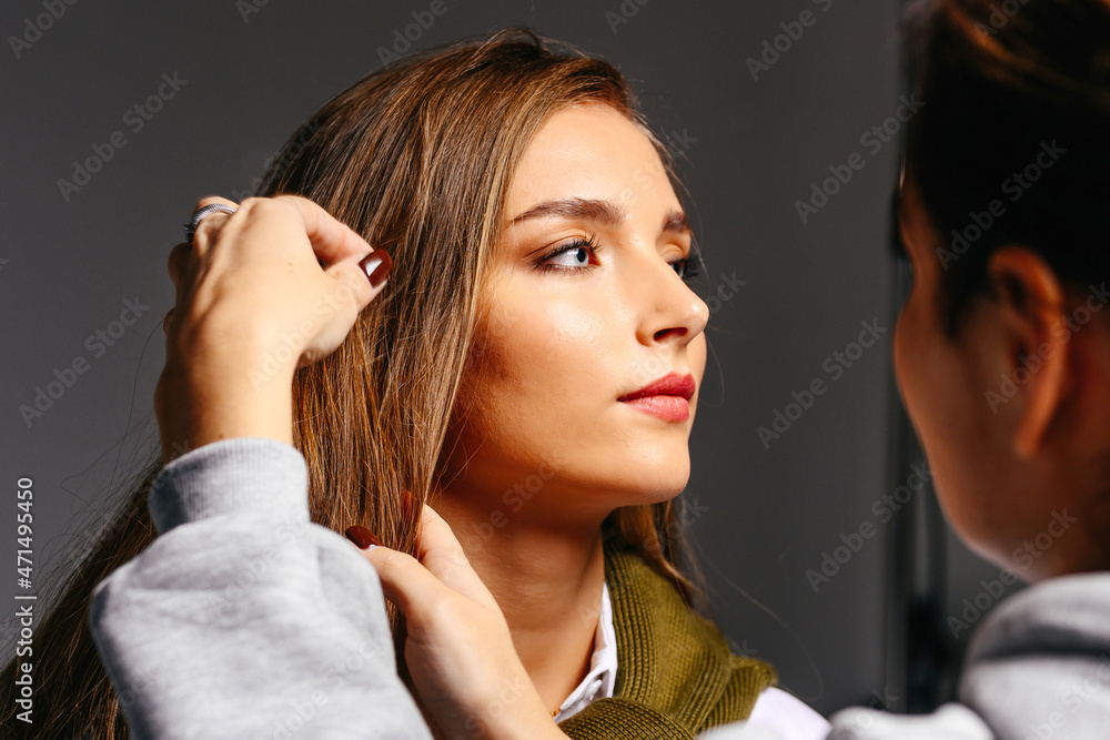 Fototapeta premium A beautiful young girl with long hair and blue eyes is styling her hair in a beauty salon.