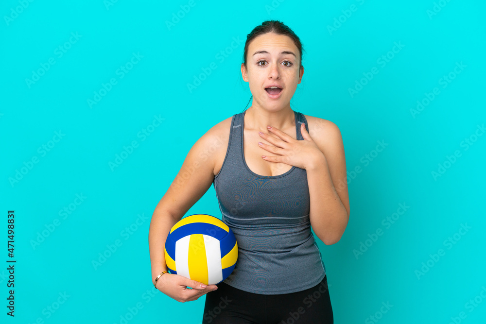 Young Ukrainian woman playing volleyball isolated on blue background surprised and shocked while looking right