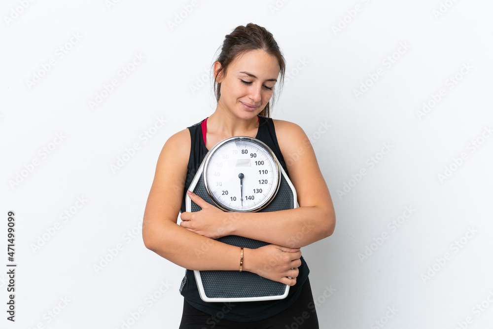 Young Ukrainian woman isolated on white background with weighing machine Young Ukrainian woman isolated on white background with weighing machine