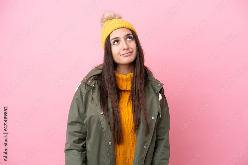 Young Ukrainian woman wearing winter jacket isolated on pink background and looking up Young Ukrainian woman wearing winter jacket isolated on pink background and looking up