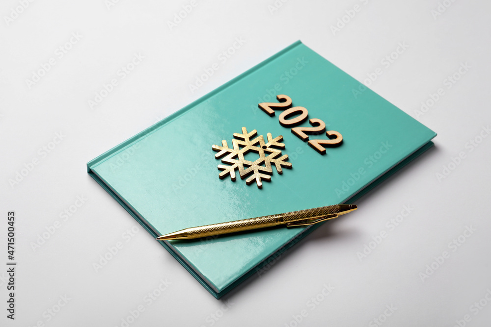 Turquoise planner, pen, wooden numbers and snowflake on white background. 2022 New Year aims Turquoise planner, pen, wooden numbers and snowflake on white background. 2022 New Year aims