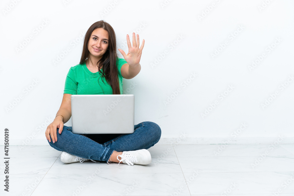 Young Ukrainian woman with a laptop sitting on floor counting five with fingers Young Ukrainian woman with a laptop sitting on floor counting five with fingers