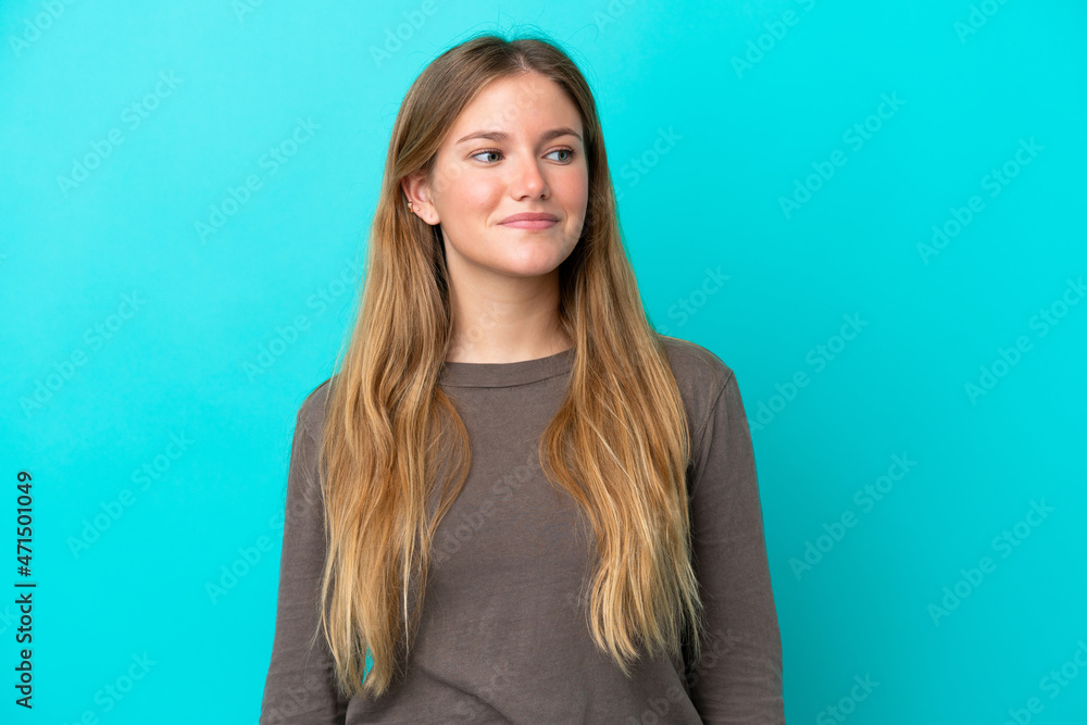 Obraz premium Young blonde woman isolated on blue background having doubts while looking side