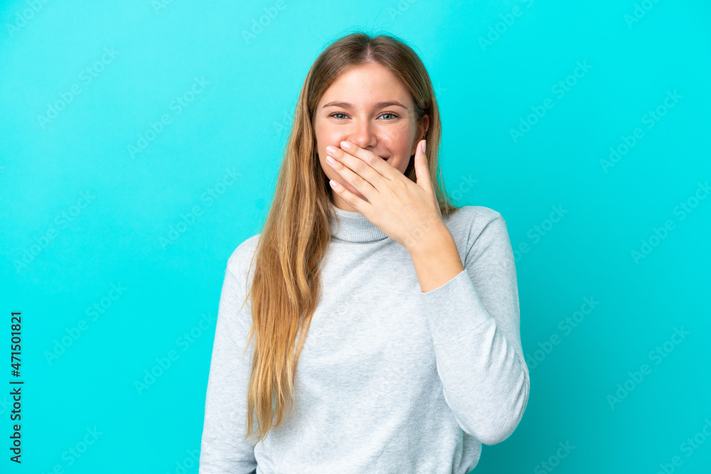 Young blonde woman isolated on blue background happy and smiling covering mouth with hand Young blonde woman isolated on blue background happy and smiling covering mouth with hand