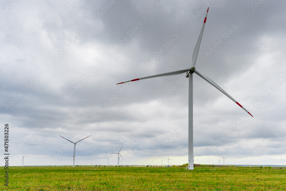 Large wind turbines with blades in the wind park on the background cloudy sky. Large wind turbines with blades in the wind park on the background cloudy sky.