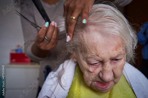 caregiver, cutting her elderly woman hair
