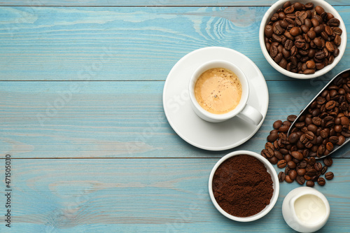 Flat lay composition with coffee grounds and roasted beans on light blue wooden table  space for text