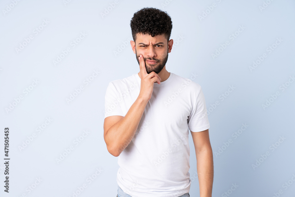 Young Moroccan man isolated on blue background and thinking Young Moroccan man isolated on blue background and thinking