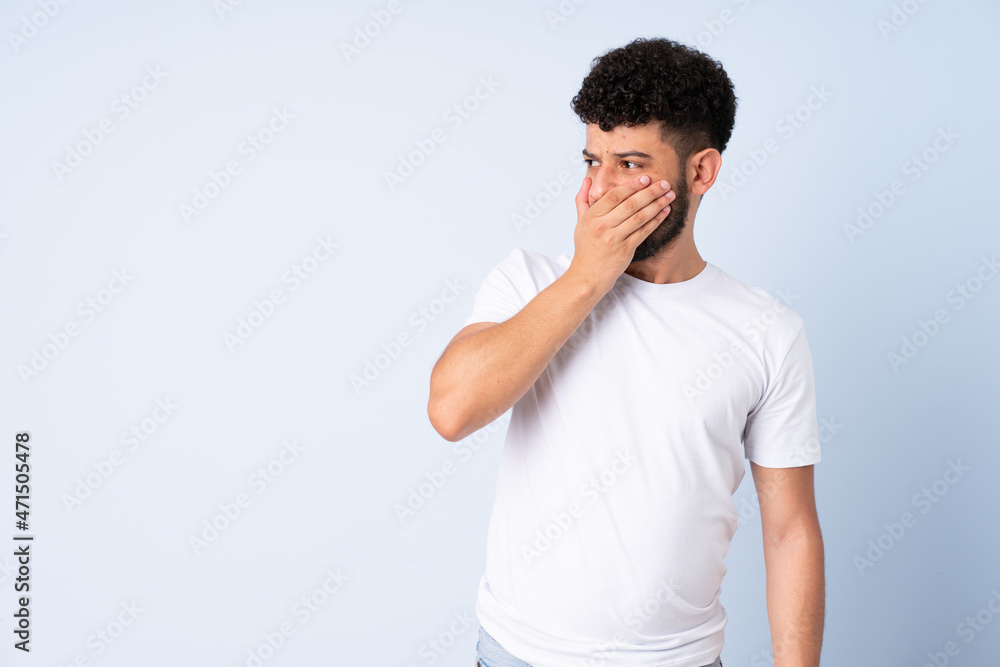 Young Moroccan man isolated on blue background doing surprise gesture while looking to the side Young Moroccan man isolated on blue background doing surprise gesture while looking to the side